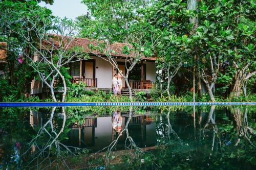 a house in the jungle with a reflection in the water at An Nhien Retreat Phu Quoc with Yoga Daily & Beach access in Phu Quoc