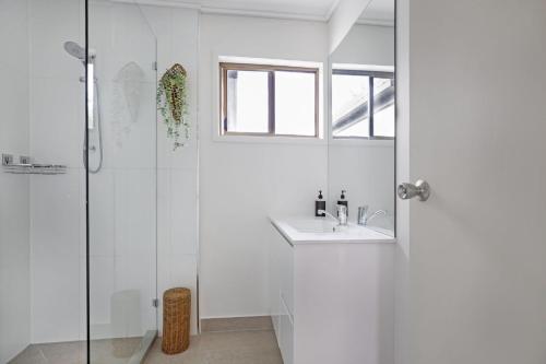 a white bathroom with a sink and a shower at Woodside Townhouse Peregian Beach in Peregian Beach