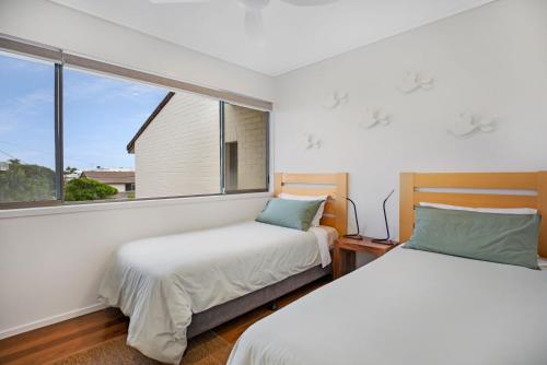 two beds in a room with a window at Woodside Townhouse Peregian Beach in Peregian Beach