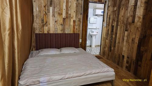 a bed in a room with a wooden wall at Vừng Homestay - Taxua in Bắc Yên