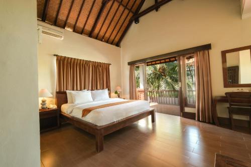 una camera con un grande letto e un balcone di Artini Bisma Ubud Hotel ad Ubud