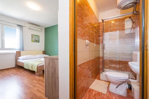 a bathroom with a shower and a toilet and a bed at Studio and Rooms Zadar City Wall in Zadar