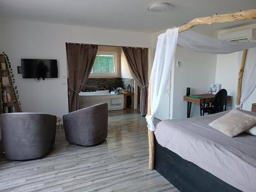 a bedroom with a bed and two chairs and a television at séjour bien-être balnéothérapie en vallée heureuse à Sorede in Sorède