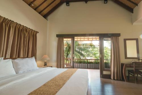 a bedroom with a large bed and a balcony at Artini Bisma Ubud Hotel in Ubud