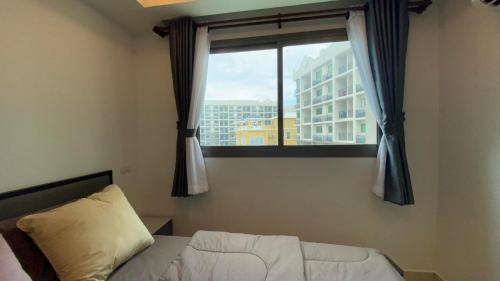 um quarto com uma cama e uma janela com um edifício em Arcadia Beach Continental em South Pattaya