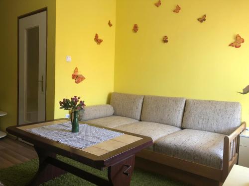 a living room with a couch and a table with butterflies on the wall at Viola Vendégház Mezőkövesd in Mezőkövesd