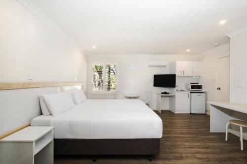 a white bedroom with a bed and a kitchen at Bayview Geographe Resort Busselton in Busselton