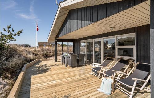 a wooden deck with two chairs and a table on it at 3 Bedroom Cozy Home In Ringkøbing in Ringkøbing