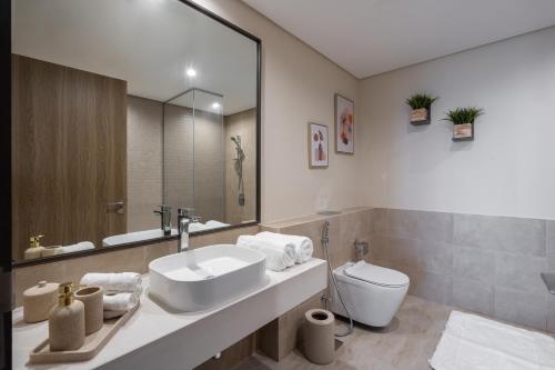 a bathroom with a sink and a toilet and a mirror at TH-Homes scandinavia interior 1 BR at Wasl 1 in Dubai