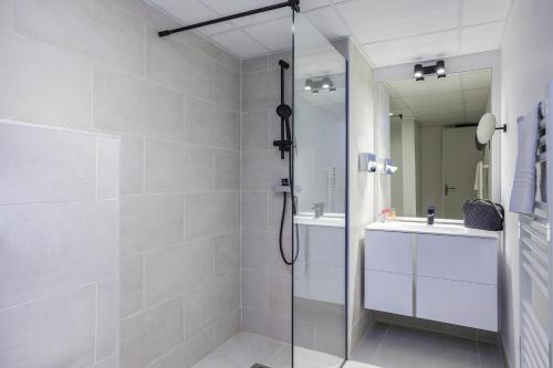 a white bathroom with a shower and a sink at Aparthotel Adagio Montpellier Centre Comedie in Montpellier