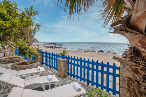 a beach with a blue fence and chairs and the ocean at Casa d' Acqua in Archangelos