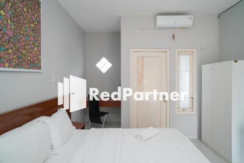 日惹House Acasia Syariah near Universitas Aisyiah Yogyakarta Mitra RedDoorz的卧室里有一张白色的床，墙上挂着一幅画