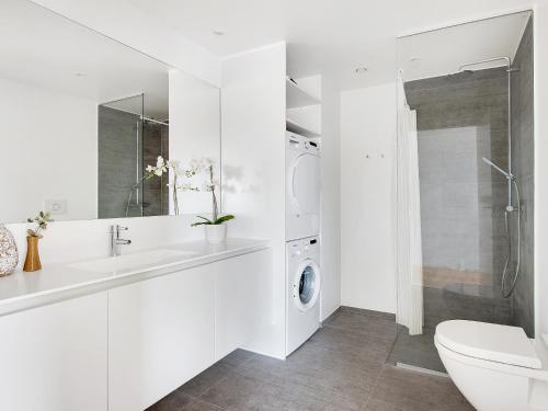 uma casa de banho branca com um lavatório e uma máquina de lavar roupa em Sanders Arena - Chic Three-Bedroom Apartment Close to Metro Station em Copenhague