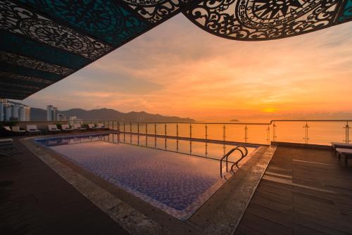 a pool on the roof of a building with a sunset at Navada Beach Hotel in Nha Trang