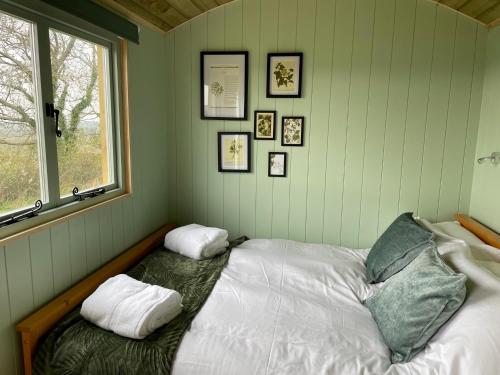 a bedroom with a bed with two pillows and a window at Cosy Shepherd Huts near Newborough Forest Anglesey in Gaerwen