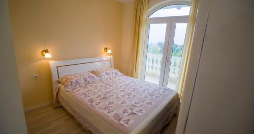 een slaapkamer met een bed naast een raam bij Вила Жаклин - Private House Jaklin with Pool in Sveti Vlas