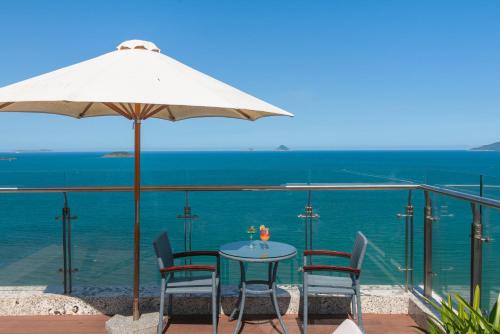 a table with chairs and an umbrella and the ocean at Navada Beach Hotel in Nha Trang