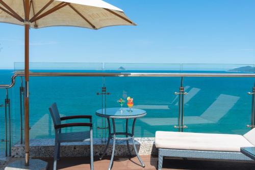 a table with two chairs and an umbrella and the ocean at Navada Beach Hotel in Nha Trang
