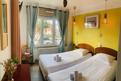 a hotel room with two beds and a window at Hotel Bistrot FINE in Anglet