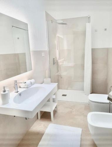 a white bathroom with a sink and a toilet at La Bella Vita in Cagliari