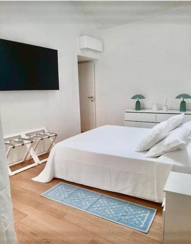 a white bedroom with a bed and a flat screen tv at La Bella Vita in Cagliari