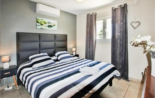 レ・アングルにあるStunning Home In Les Angles With 3 Bedrooms, Wifi And Outdoor Swimming Poolのベッドルーム1室(大型ベッド1台、ストライプ枕付)
