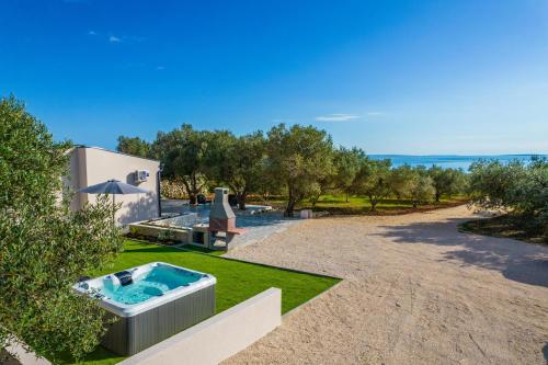 une cour avec un bain à remous sur la pelouse dans l'établissement Villa Grioni, beach front villa with jacuzzi, à Novalja