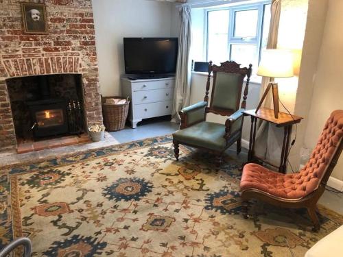 a living room with two chairs and a fireplace at Beautiful cottage in country village near Longleat in Maiden Bradley