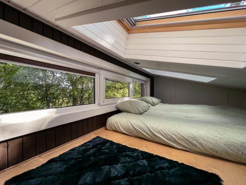 a bedroom with a bed and a window at Strazdu Ligzda Off grid treehouse in Meņģele