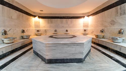 a bathroom with four sinks and a largeolith in the middle at Clover Magic Seagate Belek in Antalya