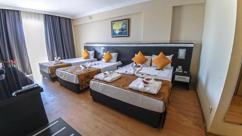 a hotel room with two beds and two tables at Clover Magic Seagate Belek in Antalya