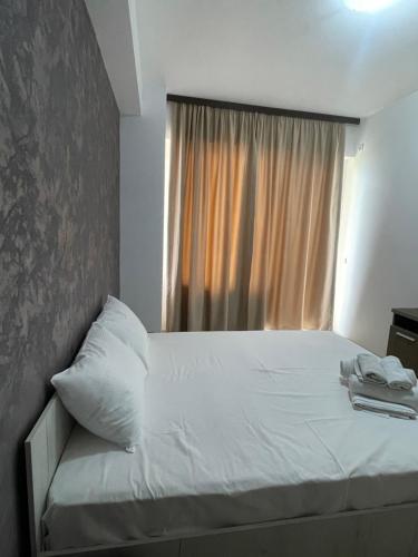Schlafzimmer mit einem weißen Bett und einem Fenster in der Unterkunft Kiraz Apartament Summerland in Mamaia