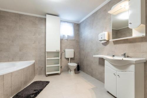 a bathroom with a sink and a tub and a toilet at Napsugár & Virág Apartman 4 csillagos in Tiszafüred