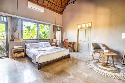 een slaapkamer met een bed en een tafel en een aantal ramen bij The Pause Inn - Soca 3 in Ubud