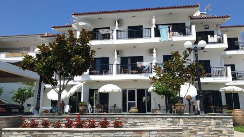 a large white building with tables and chairs at PANSION ALEXANDROS BY THE SEA in Nea Skioni