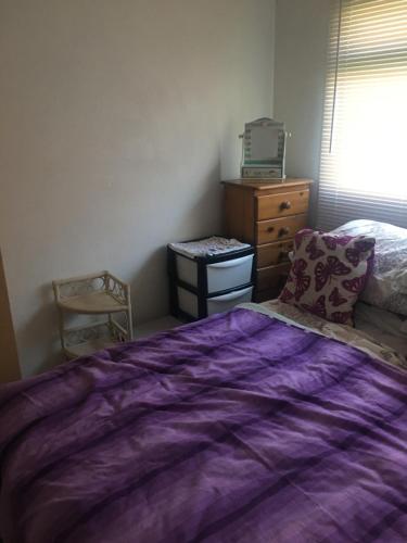 a bedroom with a purple bed and a dresser at Drop Anchor in Dartmouth