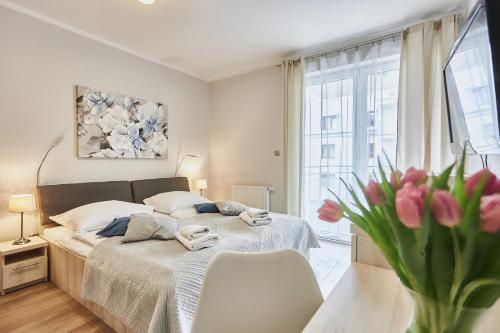 1 dormitorio con 1 cama y un jarrón de flores rosas en Pegaz Apartament, en Świnoujście