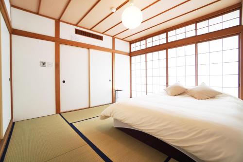 a bedroom with a white bed in a room with windows at Kagetsu 2nd Building in Osaka