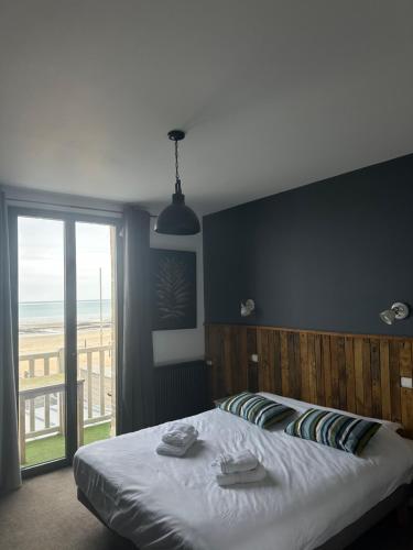 een slaapkamer met een bed en uitzicht op het strand bij Papagayo in Saint-Aubin-sur-Mer