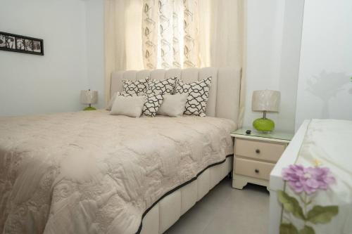 een witte slaapkamer met een groot wit bed met kussens bij Luxury Apt Ibr Naco 1br Poolgym in Santo Domingo