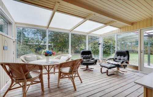 a screened in porch with a table and chairs at Holiday Home Østersvej Glesborg X in Fjellerup Strand