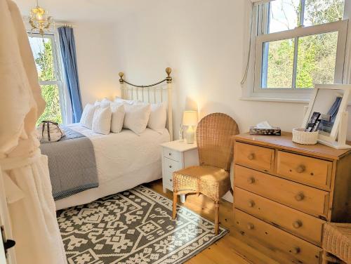 a bedroom with a bed and a dresser and a window at Romantic Secluded Hideaway Cottage in Cornwall in Truro