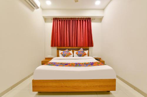 a bedroom with a large bed with a red curtain at FabHotel Happinex in Surat