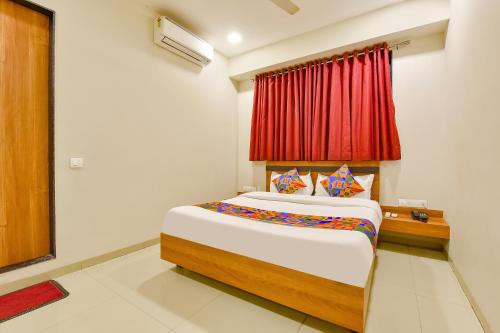 ein Schlafzimmer mit einem Bett mit einem roten Vorhang in der Unterkunft FabHotel Happinex in Surat