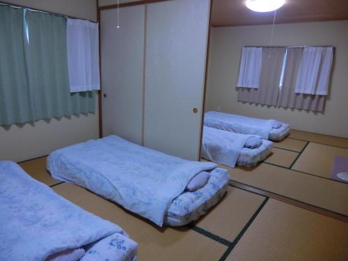 una camera con tre letti in una stanza con di ペンション石田 a Nii