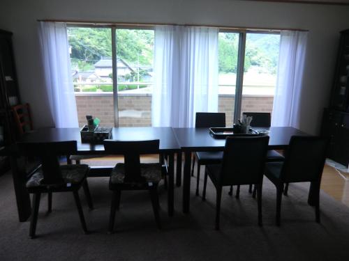 tavolo da pranzo con sedie e ampia finestra di ペンション石田 a Nii