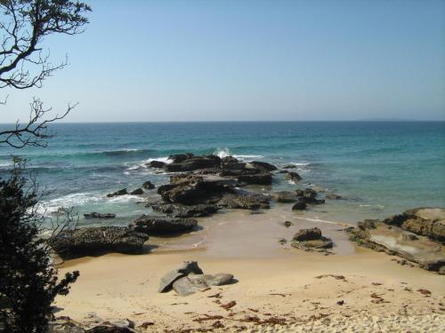 a beach with rocks and the ocean on a sunny day at Luxury Cabin Bawley Ridge Farm, dog friendly in Termeil