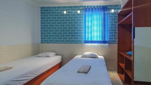 2 camas en una habitación pequeña con ventana en Reddoorz @ Homestay Gayatri en Malang