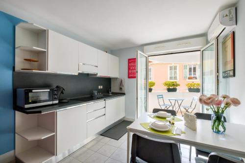 - une cuisine avec des placards blancs et une table à manger dans l'établissement Studio a Nice, à Nice