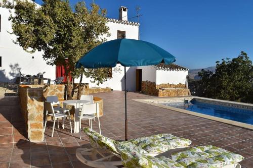 una mesa con sillas y una sombrilla junto a la piscina en Gîte rural 100 % authentique (8 pers) avec piscine, en Los Arenales